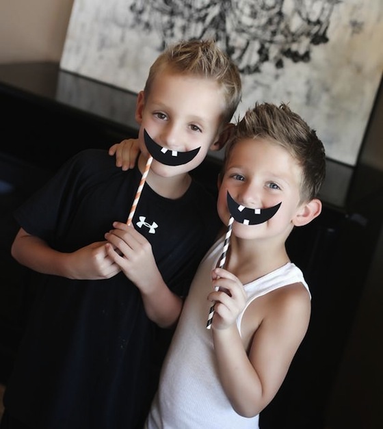 Two little boys at Halloween party holding jack-o-lantern grins